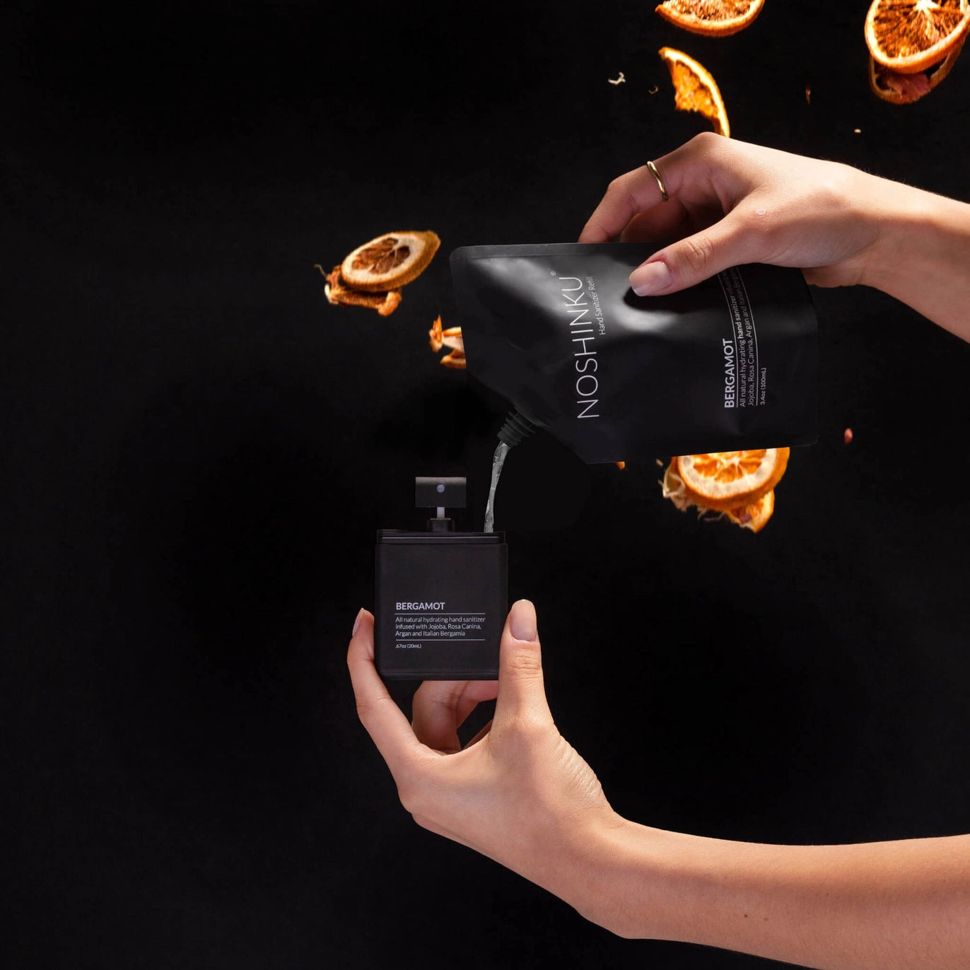 Refilling Noshinku Bergamot moisturizing hand sanitizer spray using a refill pouch with bergamot citrus scent inspiration. Exclusively at Area Boutique.