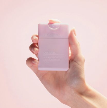 Hand holding Noshinku Lavendula refillable moisturizing hand sanitizer spray in soft purple packaging. Exclusively at Area Boutique.